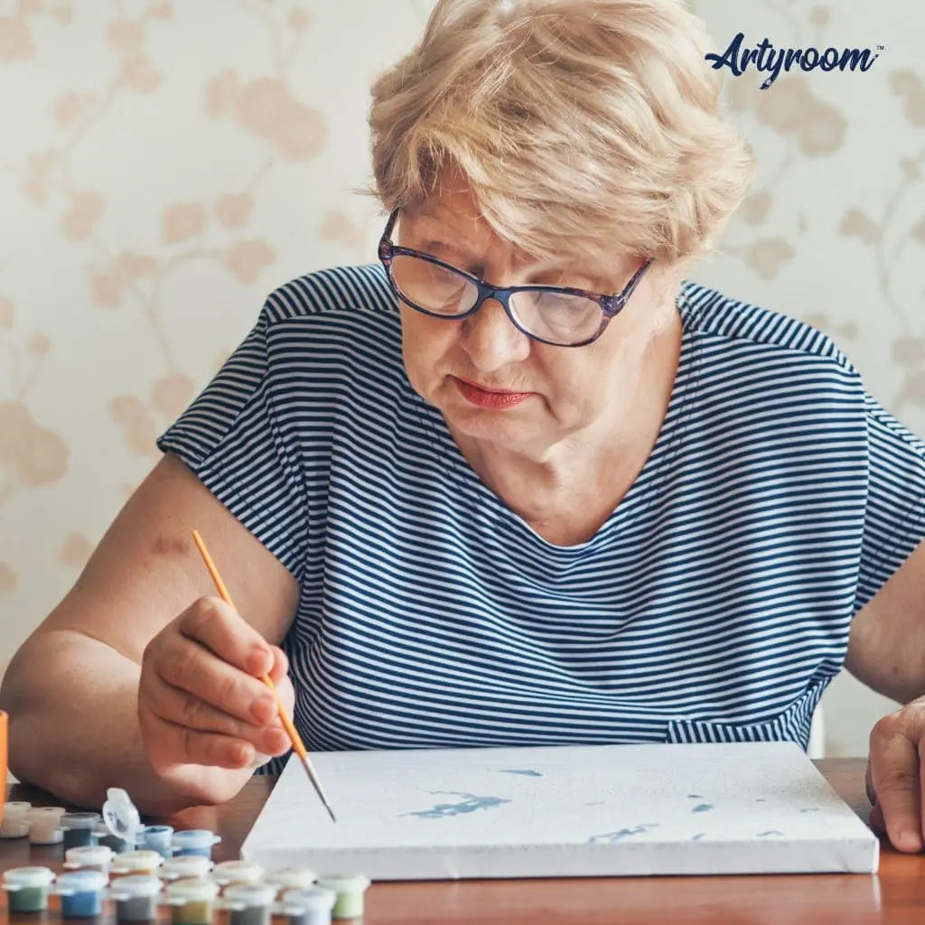 Ältere Frau beim Malen nach Zahlen mit Pinsel und Farbtöpfchen – entspannte kreative Auszeit mit Artyroom