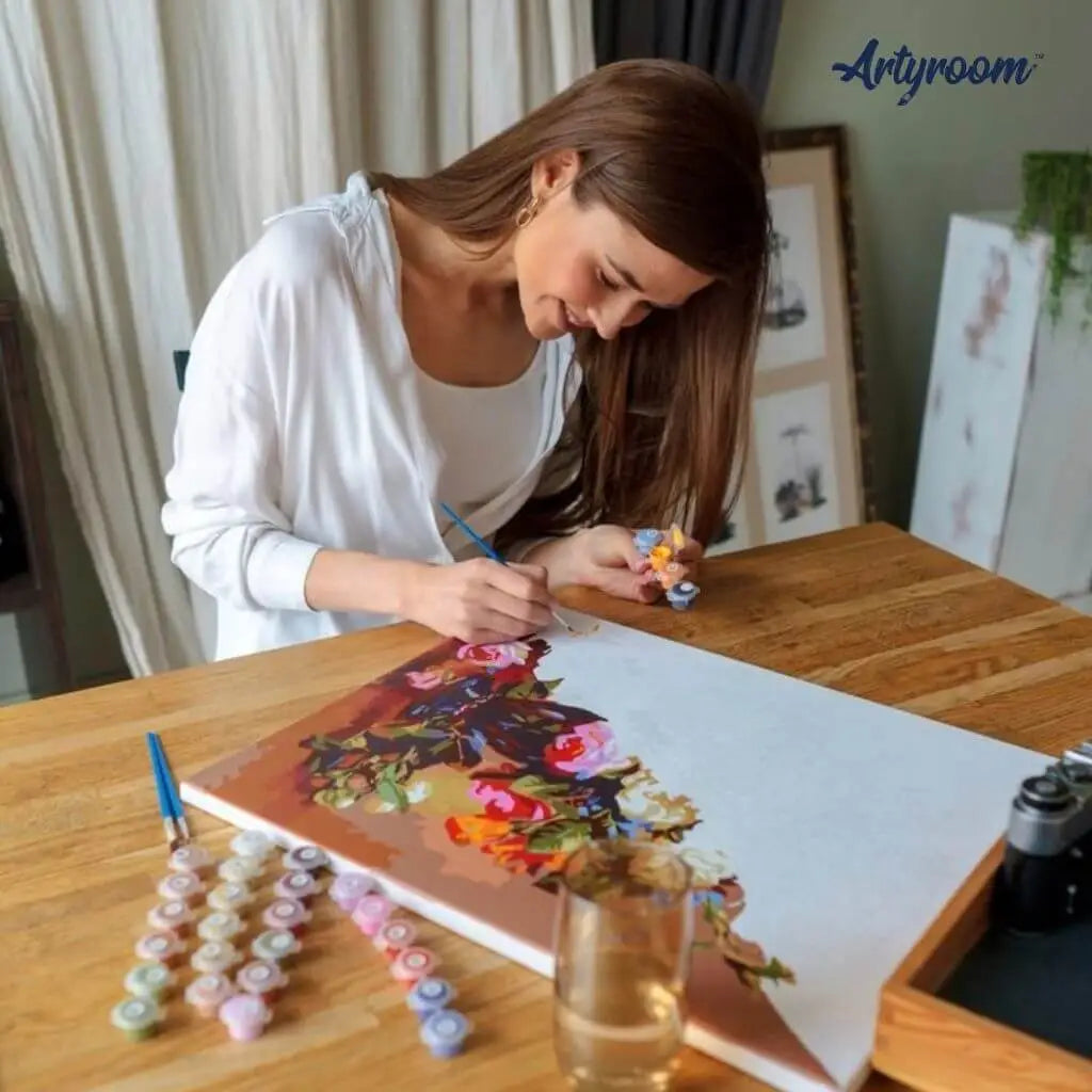 DIY Malen nach Zahlen – junge Frau malt konzentriert ein Blumenmotiv auf Leinwand mit Acrylfarben – entspannende kreative Auszeit mit Artyroom.shop