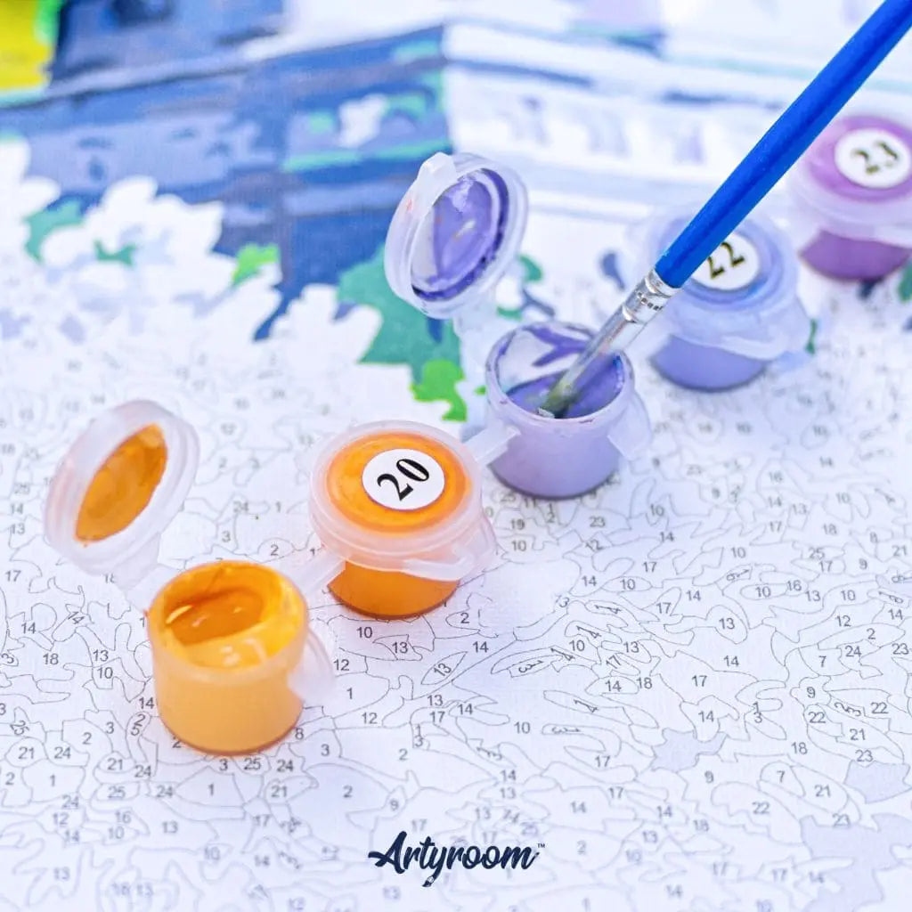 Detailaufnahme eines Malen nach Zahlen Sets von Artyroom mit geöffneten Farbtöpfchen und Pinsel beim Ausmalen der nummerierten Leinwand