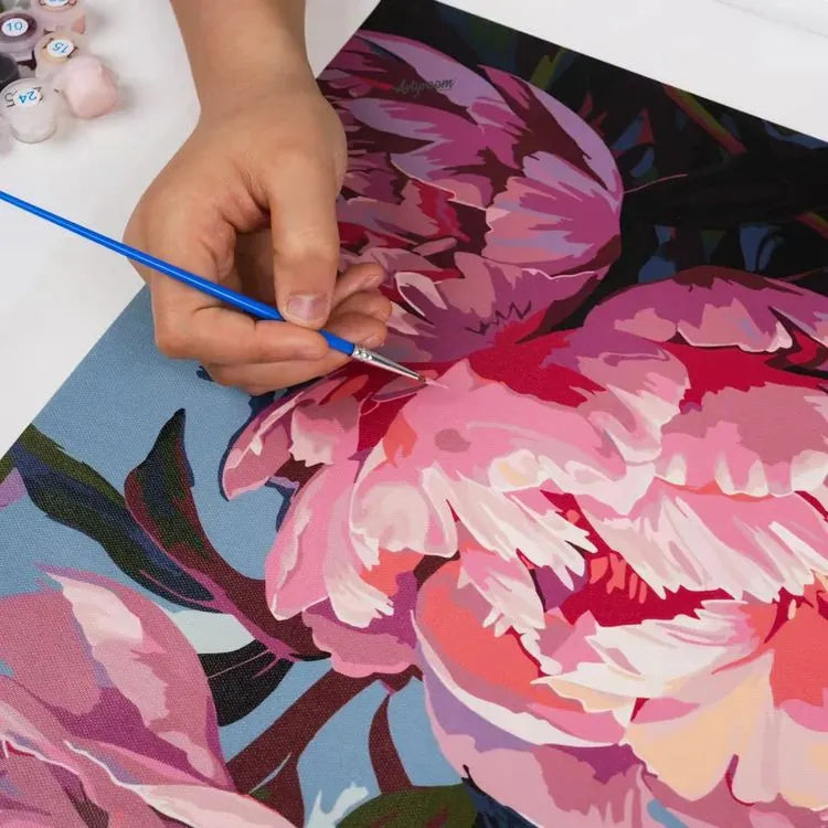 Hand hält Pinsel über nummerierter Leinwand mit Blumenmotiv – Zuordnung der Farben beim Malen nach Zahlen